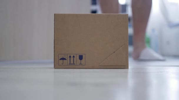 郵便配達人が配達するパッケージをドアから取っている男とのぼやけた撮影 扉における郵便配達の概念 — ストック動画