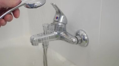 Blurred Shooting with a Person Using the Bathroom Showerhead. Man Preparing a Bath Using Hot Water from a Showerhead.