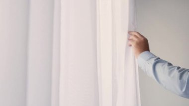 One Person Closing a White Curtain on the Window. Man Moving the Drapes on the Window in a Room.