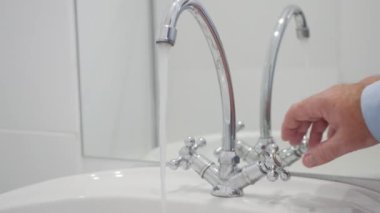 Shooting with a Person Closing a Water Tap in the Bathroom. Closing the Water from the Restroom Faucet. Wasting Water Concept.