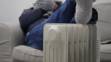 Blurred Shooting with a Man in the Sofa, on a Cold Winter Day, Dressed in Knitted Wool Clothes Trembling near a Radiator.