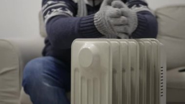 Blurred Shooting with a Man on a Cold Winter Day Dressed in Knitted Wool Clothes Trembling and Trying to Get Warm near a Radiator.