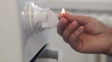 A Man Lighting Up Fire at Gas Cooker Using Matches. Close-Up Shooting with a Hand Firing a Burner in the Kitchen.