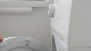 A Hand Starting and Setting the Washing Machine from a Button. Housekeeper Sets the Laundry Machine Function from Setting Panel.