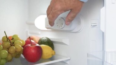 Man Hand Open the Kitchen Fridge Door and Set the Thermostat. Making the Fridge Temperature Control for Optimum Function.