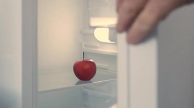 Man Hand Opens Kitchen Fridge Door and Takes an Apple. Empty Fridge, Food Crisis Concept.