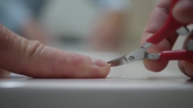 Blurred Shooting with a Man Cutting His Nails with a Scissor.  Person Making Own Manicure at Home.