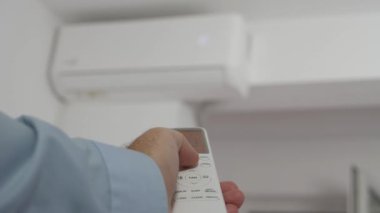 Blurred Shooting with a Man Using a Remote for an Air Conditioner. Setting the Climate in a Room Using the Air Conditioner Remote.