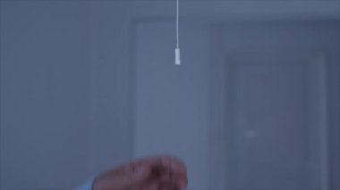 One Person Pulls the Switch Cord Turning On the Light in a Room. Opening the Light in Office. Saving Electricity Economy Concept.