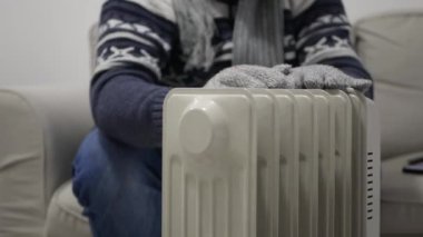 Blurred Shooting with a Man on a Cold Winter Day Dressed in Knitted Wool Clothes Trembling and Trying to Get Warm near a Radiator.