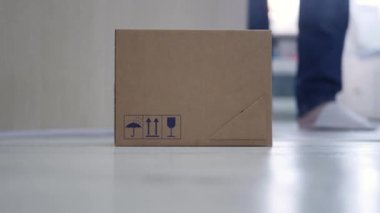 Blurred Shooting with a Man Taking from the Door a Package Delivered by Mail Courier. Concept of Postage Delivery on the Door.