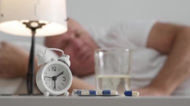 Blurred Shooting with a Sick Senior Sitting in the Bed and Taking medicines. Old Person in a Hospital Taking Medical Pills.