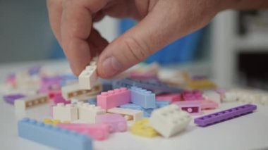 Blurred Shooting with an Elderly Person Playing Like a Child with Colorful Small Toy Bricks on the Table.