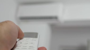 Blurred Shooting with a Man Using a Remote for an Air Conditioner. Setting the Climate in a Room Using the Air Conditioner Remote.