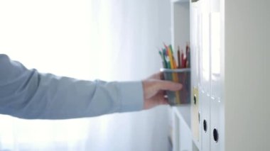 Blurred Shooting with a Person Working with Documents at the Office. Businessman Taking a Bunch of Coloured Pencils from a Shelf.