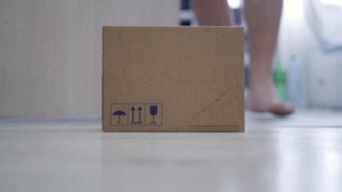 Blurred Shooting with a Man Taking from the Door a Package Delivered by Mail Courier. Concept of Postage Delivery on the Door.