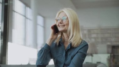 Güzel orta yaşlı sarışın kadın cep telefonuyla konuşuyor.