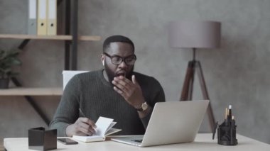 Yorgun Afrika kökenli Amerikalı erkek öğrenci iç çekerek oturur. Stresli ya da aşırı yorgun hisseder. Yorgun adam uykusuzluktan muzdariptir.