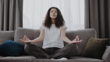Sakin Afrikalı Amerikalı kadın evdeki kanepede yoga egzersizleri yapıyor. Stres azaltma konsepti..