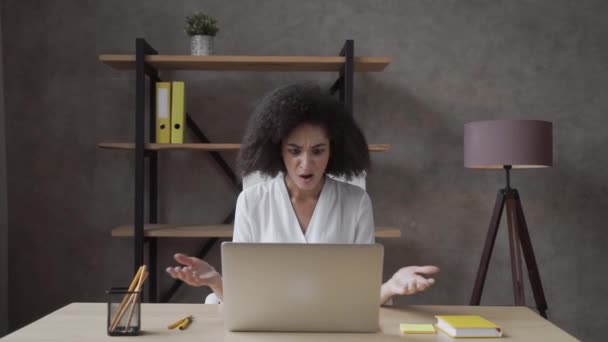 混乱した若いアフリカ系アメリカ人の女の子は ガジェットのソフトウェアの問題を持つノートパソコンの画面を見て机の上に座る 欲求不満女性は怒って不満経験のトラブル遅いインターネットやデータ損失を感じる — ストック動画