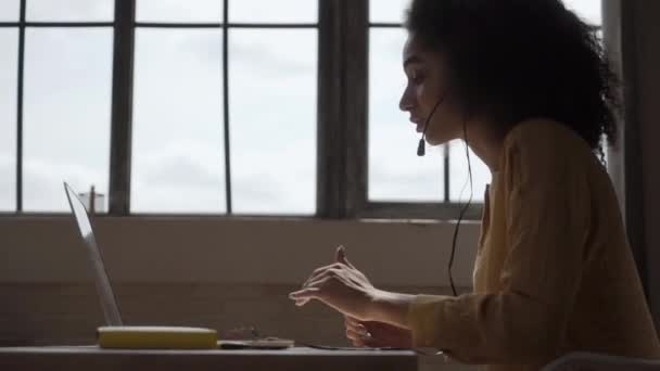 Leende Afroamerikansk Kvinna Med Headset Med Bärbar Dator Pratar Arbetar — Stockvideo