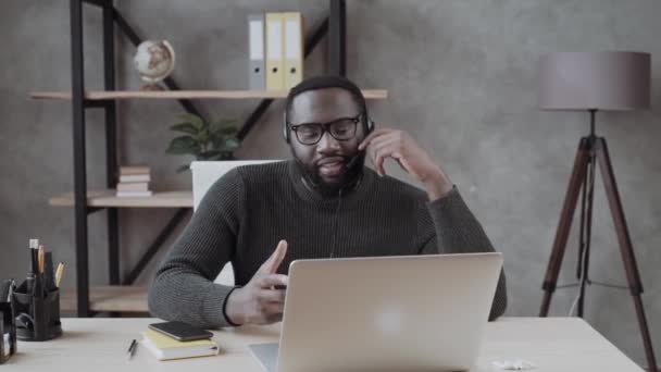 Афроамериканец Наушниках Консультируется Интернете Помощью Ноутбука Человек Наушниках Ведет Онлайн — стоковое видео