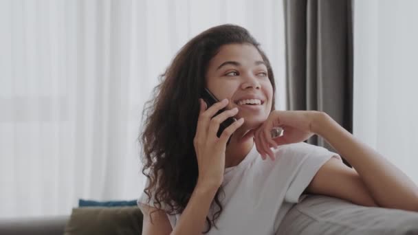 Alegre Chica Negra Hablando Teléfono Móvil Con Novio Sentado Sofá — Vídeos de Stock