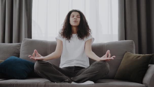 平静的非洲裔美国女人 专注于在家里沙发上做瑜伽练习 减轻压力的概念 — 图库视频影像