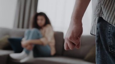 Erkek eli yakın oturduğu yerde oturan ve kendini koruyan karısını dövmeye hazır. Aile içi şiddet, saldırganlık suçu kavramı..