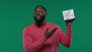 Gülümseyen mutlu, neşeli, Afro-Amerikalı 20 'li yaşlarda. Yeşil duvar arka planında izole edilmiş hediyeleri var.