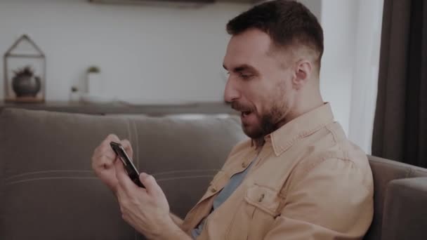 Jovem Homem Bonito Feliz Segurando Telefone Celular Sentindo Animado Obter — Vídeo de Stock