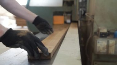 İşçi ahşap işleme makinesinde ahşap tahta tutuyor. Başla. Eldiven işçisi, ahşap işleme için modern işletmedeki otomatikleştirilmiş makinede ahşap tahta işliyor.