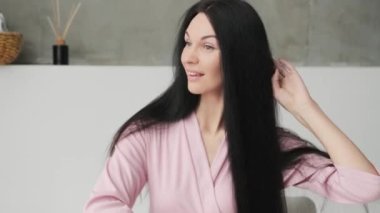 Çekici bir kadın banyoda uzun, kumral, uzun saçlarını tarıyor..