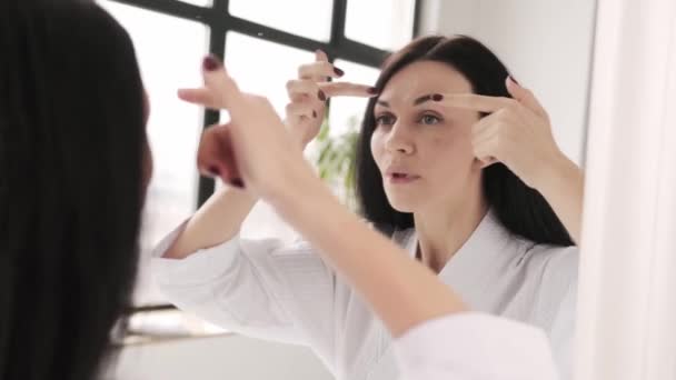 Seorang Wanita Menyentuh Jerawat Dahinya Saat Melihat Cermin — Stok Video