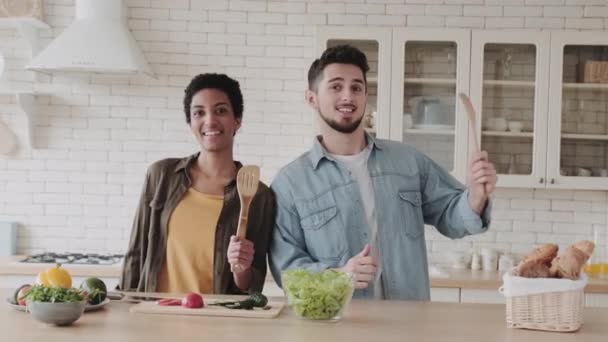 Счастливая Многонациональная Пара Кухне Возле Салатов Овощей Кухонными Принадлежностями Руках — стоковое видео