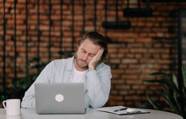 Çalışan laptopun yanındaki iş yerinde uyuyakalıyor.