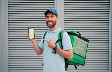 FOOD DELIVER duvarın arka planında boş bir ekranı olan bir akıllı telefon gösterir.