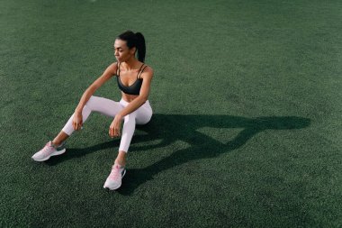 Parlak güneşli bir günde spor sahasında zayıf, genç Afrikalı bir kadının portresi.