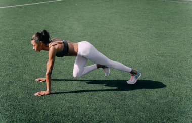 Afrikalı atletik kadın spor sahasının çimlerinde egzersiz yapıyor. Spor yapan kadın sabah vücut egzersizi yapıyor..