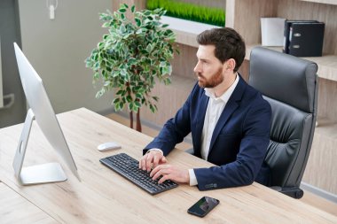 Ofiste bilgisayarla çalışan yakışıklı bir iş adamı. İş yerindeki klavyeye yazı yazmak.