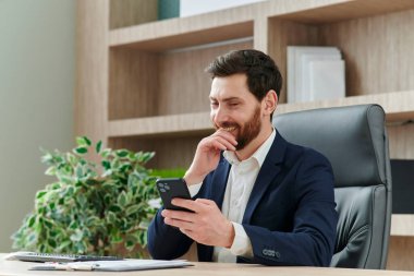 İş adamı kılığındaki işadamı telefona bakıp gülerken komik içerik ya da mesaj görür.