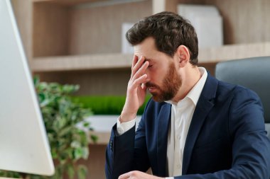 Yorgunluktan, baş ağrısından ve migrenden gözlerini kapayan bir yönetici ya da ofis çalışanı..