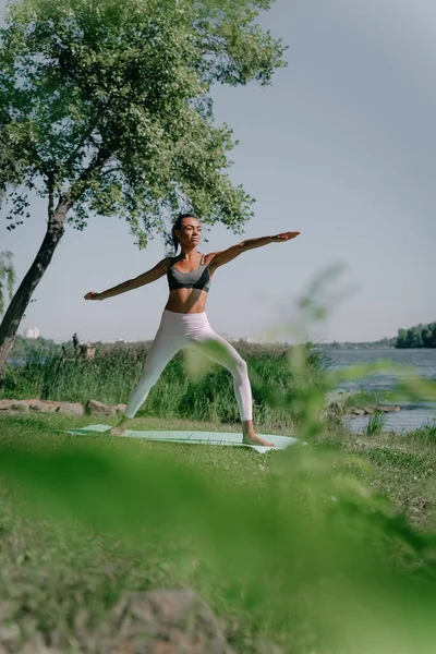 Genç ve güzel Afrikalı kız açık mavi gökyüzü ile güzel bir günde yoga savaşçısı pozu veriyor. Güzel bir bahar gününde güzel bir Afrikalı Amerikalı kadın gevşeme egzersizi yapıyor..