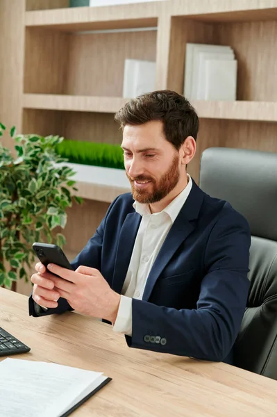 İş adamı gülümsüyor ve ofisteki akıllı telefonuna bir mesaj yazıyor. Takım elbise giyiyor, modern ve güzel bir ofiste çalışıyor..