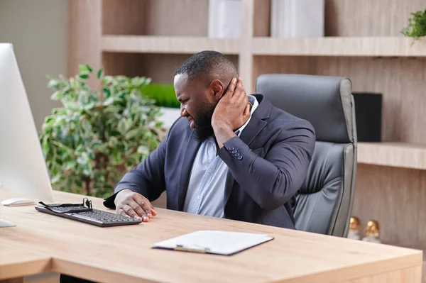 CEO 'nun iş yerinde boyun sorunları olur. İş elbisesi giymiş Afro-Amerikalı ofis çalışanı ekşi kaslar ve boyun ağrısı. İş yerinde sağlık sorunları.