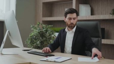 Ofisinde bazı veri ve çizelgeleri olan yakışıklı bir profesyonel. Yoğunlaşmış ve meşgul görünüyor..