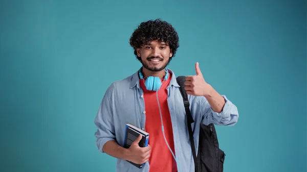 幸せな若い大人の研究室や青の背景に隔離された立っているインドの男学生を笑顔 良いサービスや結果を広告推薦を与える手ジェスチャーのような親指を表示します — ストック写真