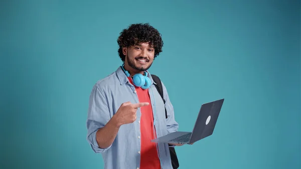 Jóképű Indiai Diák Kék Háttérrel Kezében Egy Laptoppal Egy Kézmozdulattal — Stock Fotó