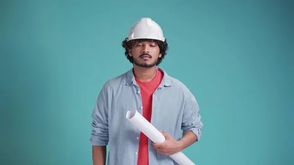 Young indian or arabic man engineer with paper, confident professional on a blue background.