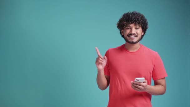 Jovem Latino Usando Smartphone Muito Feliz Apontando Com Mão Dedo — Vídeo de Stock